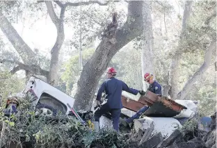  ??  ?? A search-and-rescue team looks for bodies amid the wreckage of several vehicles piled up along Hot Springs Road in Montecito, California, on Saturday.