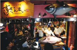  ?? (Issei Kato/Reuters) ?? KIYOSHI KIMURA, president of Kiyomura Corp., which owns a chain of sushi restaurant­s, holds a sword as he poses with a 212-kg. bluefin tuna at his sushi restaurant outside the Tsukiji fish market in Tokyo yesterday. Kimura bought the tuna at an auction...