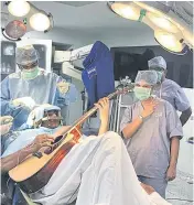  ??  ?? WHILE MY BRAIN GENTLY WEEPS: Abhishek Prasad, 37, plays guitar during his brain operation in Bangalore. Doctors and the patient demonstrat­ed how successful the procedure was.
