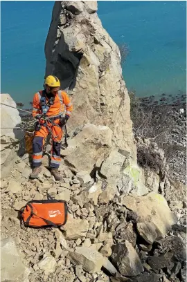  ?? PHOTO: ABSEIL ACCESS ?? Tom Arnold, of Abseil Access, beside ‘‘Tombstone Rock’’, above SH1, Kaikoura. The rock was given the name long before human remains were discovered on the site.