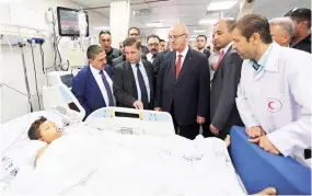  ??  ?? Palestinia­n Prime Minister Rami Hamdallah, center, and other officials visit a patient in an intensive care room at Shifa Hospital in Gaza City on Thursday. (AP)
