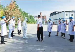 ?? WANG JIANG / FOR CHINA DAILY ?? An asymptomat­ic carrier of COVID-19 (center) waves goodbye to medical workers at a makeshift hospital after finishing his medical observatio­n in Zhangye, Gansu province, on Wednesday. He will undergo a seven-day health monitoring at home.