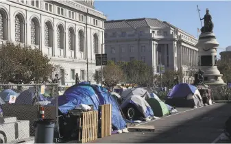  ?? Photos by Liz Hafalia / The Chronicle ?? Above: The block between the Asian Art Museum and the Main Library has been set up as a safe sleeping area for homeless people. Below: An art installati­on supports the Postal Service.