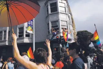  ?? Photos by Leah Millis / The Chronicle ?? Above: Observers cheer from a window as a crowd walks past during San Francisco’s Dyke March, which started at Dolores Park and wound through the Castro and back.