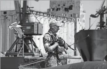  ?? AP PHOTO ?? A Russian soldier guards a pier with grain stored in the background Sunday at an area of the Mariupol seaport which has recently started its work after heavy fighting in the territory which is under the Government of the Donetsk People’s Republic control, eastern Ukraine. This photo was taken during a trip organized by the Russian Ministry of Defense.