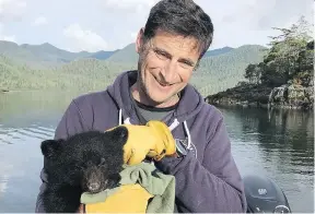  ?? THE CANADIAN PRESS ?? John Forde comforts an orphaned bear cub after he rescued it in Ross Pass. The animal, between eight and 12 weeks old, is now in a wildlife recovery centre.