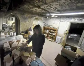  ??  ?? Above: Ms. Johnson, selects some of the tiles in the storage area of the ceramics studio at the library.