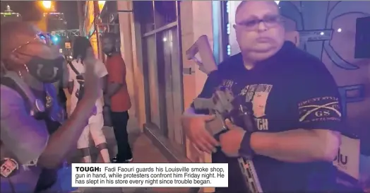  ??  ?? TOUGH: Fadi Faouri guards his Louisville smoke shop, gun in hand, while protesters confront him Friday night. He has slept in his store every night since trouble began.