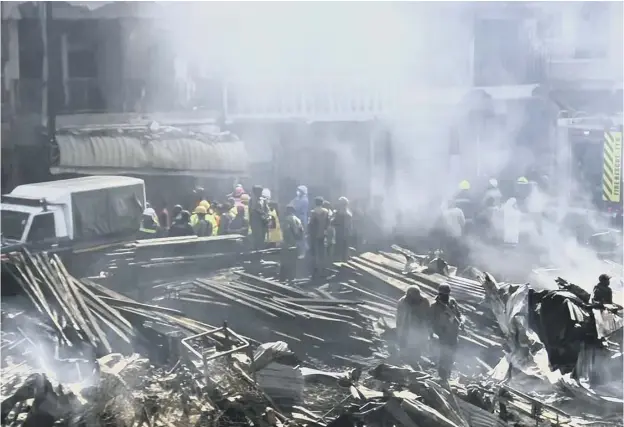  ??  ?? 0 Emergency services work at the scene after a fire swept through a marketplac­e in Nairobi, leaving at least 15 people dead