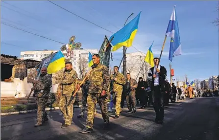  ?? ?? THE FUNERAL procession for 32-year-old soldier Oleksii Kozlenko proceeds up Tsentralna street in Borodyanka last week.