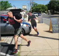  ?? Photo by Ernest A. Brown ?? Industrial Revolution Crossfit club members head back to the gym after a morning run carrying sandbag weights.