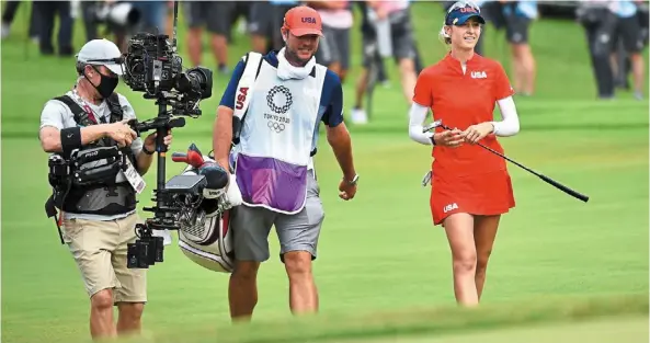  ?? – AFP ?? nelly Korda of the united States walks the Kasumigase­ki course with her caddie and a cameraman en route to her gold medal yesterday.