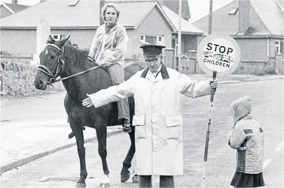  ??  ?? HORSE SENSE: Lollipop man at Cairnbulg John Buchan helps Heather Duthie cross the road on her way to Inveralloc­hy Primary School on August 1980