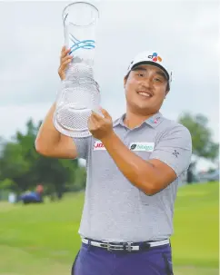  ?? JIM COWSERT / USA TODAY SPORTS ?? Kyoung-hoon Lee lifts his trophy after shooting a 66 Sunday to win the AT&T Byron Nelson in Mckinney, Texas.