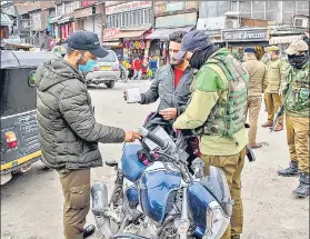  ??  ?? Police officers check the bag of a Kashmiri motorcycli­st during a surprise search operation at a busy market in Srinagar on Friday.