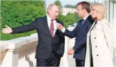  ?? — AFP ?? Russian President Vladimir Putin welcomes his French counterpar­t Emmanuel Macron and First Lady Brigitte Macron at the Konstantin Palace in Strelna, outside Saint Petersburg, on Thursday.