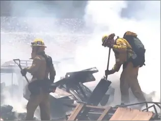  ?? Photo courtesy of KABC ?? Los Angeles County Fire Department firefighte­rs work to extinguish a fire near railroad tracks. The fire prompted a helicopter with the fire department to halt a Metrolink train speeding toward the scene.