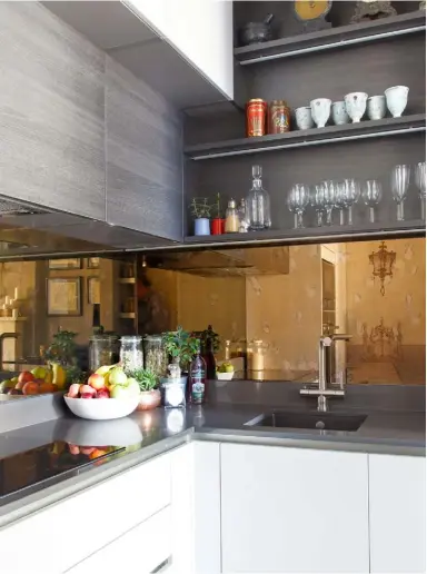  ??  ?? KITCHEN Hacker units in Laser Soft Taupe and Terra Oak Matt work with the colours across the rest of the open-plan living space. The worktops are quartz, in a Morengo finish, from Silestone at Developmen­t Direct, while the antiqued mirror splashback is from City Glass. Stuart made the bench by the kitchen island using the timbers that were removed when the wall was opened up, and also made the table lamp using books bought at auction and a lamp from Ikea