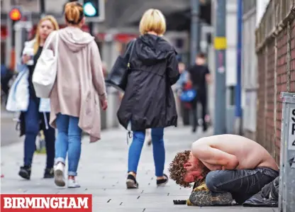  ??  ?? At rock bottom: A half-naked man bends over double as he sits begging from pedestrian­s