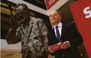  ?? Sean Gallup / Getty Images ?? Olaf Scholz stands beside a statue of ex-Chancellor Willy Brandt as he announces his Cabinet choices.