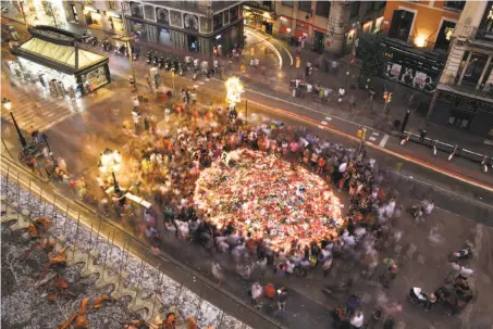  ?? Manu Fernandez / Associated Press ?? People gather at a memorial tribute of flowers and candles to the terror attack victims on Barcelona’s Las Ramblas promenade.