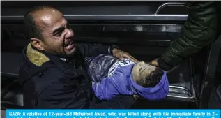  ?? — AFP ?? GAZA: A relative of 12-year-old Mohamed Awad, who was killed along with his immediate family in Zionist bombardmen­t, mourns as he holds his body at the European hospital in Khan Yunis in the southern Gaza Strip on Jan 6, 2024.