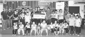  ??  ?? Magnum Cares Bintulu representa­tive Victor Lu (standing front row, fifth left) presents the RM3,000 mock cheque to Perpikat Bintulu chairman Hii Ming Hua (standing front row, sixth left) at the centre yesterday.