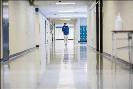  ?? ?? A middle school principal walks the empty halls of his school as he speaks with one of his teachers to get an update on her COVID-19 symptoms, Friday, Aug., 20, 2021, in Wrightsvil­le, Ga. On Monday, Dec. 27, US health officials cut isolation restrictio­ns for Americans who catch the coronaviru­s from 10 to five days, and also shortened the time that close contacts need to quarantine. (AP)