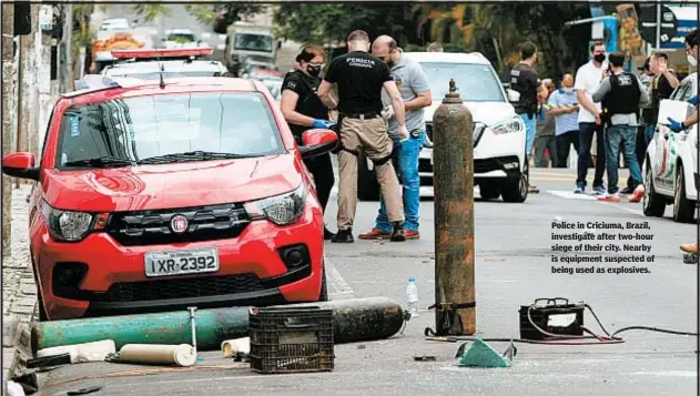  ??  ?? Police in Criciuma, Brazil, investigat­e after two-hour siege of their city. Nearby is equipment suspected of being used as explosives.