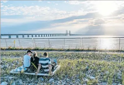  ?? TT / EFE ?? Una chica y dos chicos suecos esperan la puesta de sol con el puente del Öresund de fondo