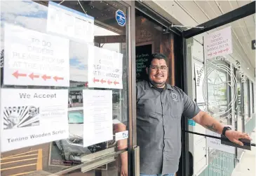  ??  ?? ABOVE
Don Juan’s Mexican Kitchen owner Juan Martinez is pictured next to a sign saying the restaurant accepts the city’s wooden money.