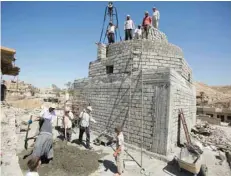  ?? — Reuters ?? Workers rebuild a Yazidi shrine, after it was destroyed by IS, in Bashiqa, a town near Mosul.