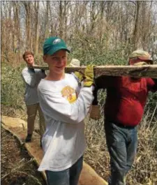  ??  ?? Andrew Manwaring, with his brother Paul, and Jim McGaffin, district commission­er for Boy Scouts, carry wood planks for placement on the new pathways in Wallingfor­d’s Furness Park.