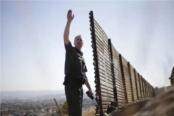  ?? GREGORY BULL/THE ASSOCIATED PRESS ?? U.S. Border Patrol agent Jerry Conlin stands at the old wall along the U.S.-Mexico border where it ends at the base of a hill in San Diego. Behind him is Tijuana, Mexico.