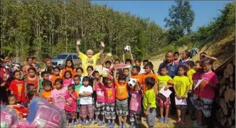  ??  ?? Hugh Cooney (back, wearing yellow) in a jungle village in Laos where he donated clothing and sports equipment to local children