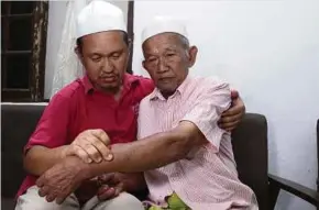  ?? (Foto Nik Abdullah Nik Omar/bh) ?? Yaakub menunjukka­n tangan yang cedera kepada anaknya ketika ditemui di rumahnya di Kampung Berangan Masjid.