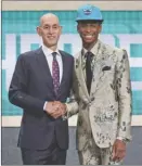  ?? The Associated Press ?? Kentucky’s Shai Gilgeous-Alexander, right, poses with NBA commission­er Adam Silver after he was picked 11th overall by the Charlotte Hornets during the NBA draft in New York on Thursday. However, he was then traded to the Los Angeles Clippers.