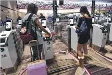  ?? Bloomberg; AFP; Reuters ?? Robotics specialist­s prepare to test drive an autonomous container trailer on the tarmac at at Changi Airport, top, where many tasks are becoming automated. Passport scanning at Terminal 4 and expansion in progress, above.