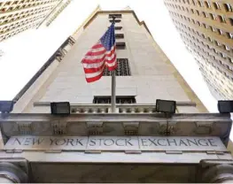  ??  ?? NEW YORK: The American flag flies above the Wall Street entrance to the New York Stock Exchange. US stock indexes held steady near record levels Friday after gains for companies that pay big dividends helped to offset drops in technology stocks. — AP