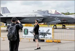  ?? AP/YONG TECK LIM ?? Visitors take a photo with a Lockheed Martin F-35B fighter jet parked at the static display area during the Singapore Airshow on Wednesday. More than 170 U.S. companies are represente­d at the show, using nearly a third of the exhibition space.