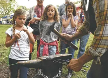  ?? STAFF FILE PHOTO ?? Blacksmith Bud LaMonica with Choo Choo Forge makes toy swords from nails for Fehnly Sneed, Isa Elles and Emery Sneed, from left, at the 2015 Hamilton County Fair.