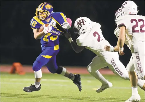  ?? H John Voorhees III / Hearst Connecticu­t Media ?? Brookfield’s Jack Mix (18) is caught by North Haven’s Albert Hooks (2) as he goes around the corner Friday night at Brookfield High School.