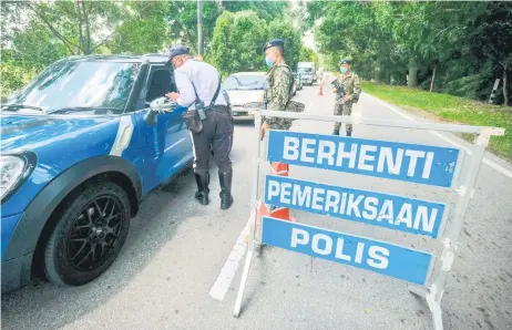  ?? — Bernama photo ?? Security forces in Melaka conduct checks for travel permits at a roadblock set up at the border of Melaka Tengah and Jasin districts yesterday. Under the MCO, inter-district and interstate travels are prohibited except for emergencie­s, health ma ers, work and economic purposes, vaccinatio­n appointmen­ts and long-distance couples.