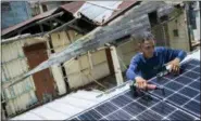  ?? DENNIS M. RIVERA PICHARDO — ASSOCIATED PRESS ?? Julio Rosario instals a solar energy system at a home in Adjuntas, Puerto Rico, on Tuesday.