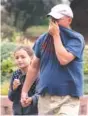  ?? GEOFF CRIMMINS/THE MOSCOW-PULLMAN DAILY NEWS VIA AP ?? Chris Karn covers his face to filter out smoke from regional wildfires while walking daughter Chloe to school Tuesday, in Moscow, Idaho.