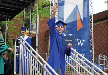  ?? WILLIAM J. KEMBLE — DAILY FREEMAN ?? Bryan Baulsir, of Saugerties, waves after receiving his diploma during Sunday’s graduation ceremonies at SUNY New Paltz.