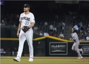  ?? PHOTOS BY ROSS D. FRANKLIN — THE ASSOCIATED PRESS ?? Diamondbac­ks relief pitcher Kevin Ginkel looks for a new baseball after giving up a three-run home run to Oakland’s Jed Lowrie, right, during the seventh inning on Tuesday in Phoenix.