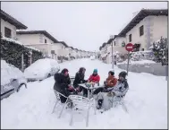  ?? (AP/Bernat Armangue) ?? Neighbors gather in the middle of a street Saturday amid heavy snowfall in Bustarviej­o, Spain.