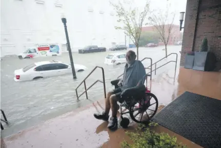  ??  ?? A man watches flood waters Wednesday in downtown Pensacola, Florida.