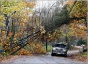  ?? AP PHOTO BY ROBERT F. BUKATY ?? A motorist drives under downed pine trees that are resting on power lines in Freeport, Maine, Monday. A strong wind storm has caused widespread power outages.